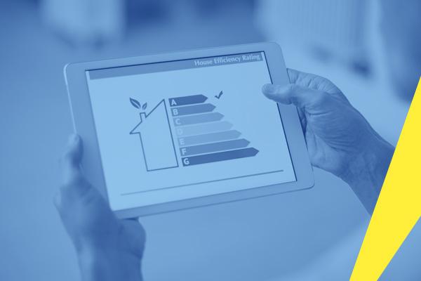 The photograph shows a person's hands, from the perspective of the person themselves, holding a tablet which displays the EU energy label